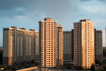 Fototapeta na wymiar Modern residential complex on the background of cloudy clouds. Weather before rain. Dark sky over city district with high-rise buildings. Aerial view of multi-storey buildings.