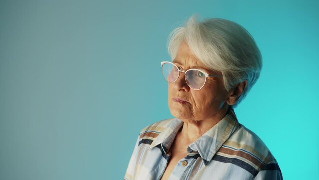 senior Caucasian woman thinking about her health problem copy space medium closeup studi shot blue background healthcare concept. High quality 4k footage