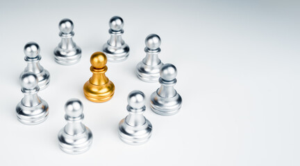 The golden pawn chess piece standing in the middle of silver pawn chess pieces group on white...