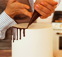 Lifestyle, people, cooking and freelance concept: Female hands decorate the cake with chocolate