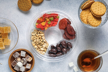 a variety of sweets dried fruits nuts cookies and tea are on the bright table