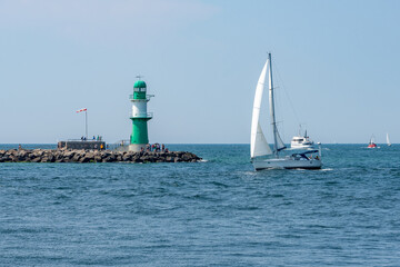 Sailboat passing the lighthouse Molenfeuer Westmole, Warnem&uuml;nde, Rostock, Mecklenburg-Vorpommern, Germany