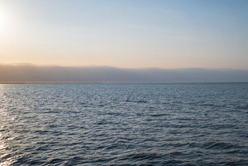Obraz premium Lake Erie with shoreline in the distance with the early evening setting sun. It is the fourth largest lake of the five Great Lakes in North America. At its deepest point it is 210 feet deep.