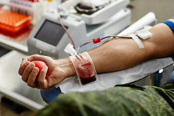 Close up of unrecognizable male donor donating blood and squeezing stress ball, copy space