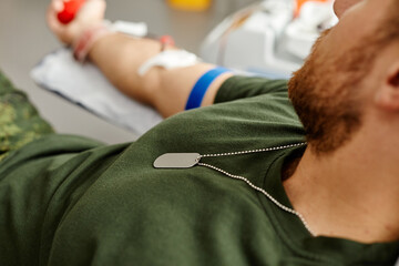 Close up of soldier donating blood at hospital center, copy space