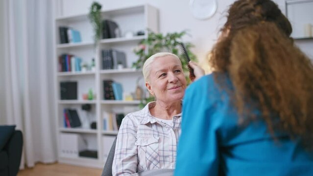 Nurse combing hair for mature woman living in retirement home, elderly care