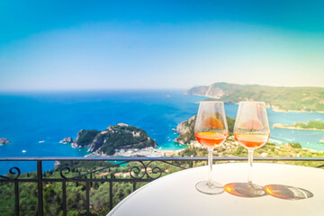 Two glasses of white wine with Corfu in background - obrazy, fototapety, plakaty