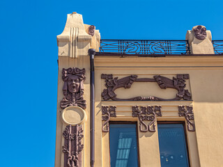 Art Nouveau mascarons on a building in Irkutsk, against the blue sky