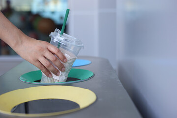 Woman hand holding throwing plastic cup in litter bin