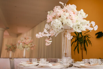 festive wedding decoration. Beautiful fresh white and pink flowers in glass vase on dining table on...