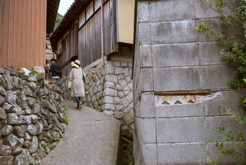 香川県・男木島　石垣の路地を歩く女性観光客　Female tourist walking through alleyway in Ogijima Island, Kagawa, Japan