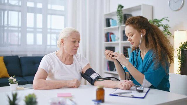 Woman therapist measuring blood pressure of senior woman, health check-up