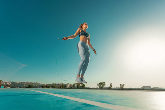 Young sportswoman training jumping on an agility ladder coordinating outdoors