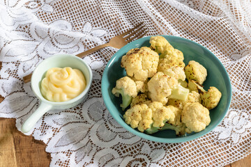 Healthy food roasted cauliflower salad in bowl dish has mayonnaise on fabric background.