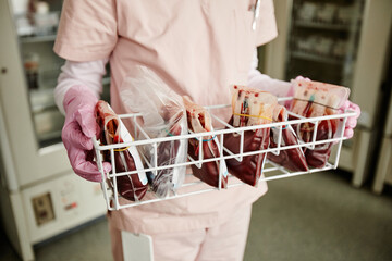 Close up of unrecognizable nurse holding tray with blood bags in donation center or clinic, copy...