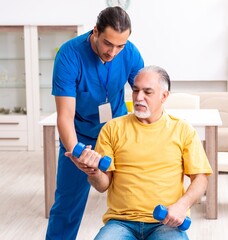 Obraz premium Young male doctor visiting old patient at home