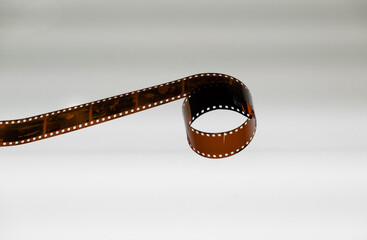 A roll of photographic film is placed on a white transparent glass table. placed in the center of...