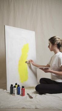 modern woman painting on canvas on plain background, studio shot