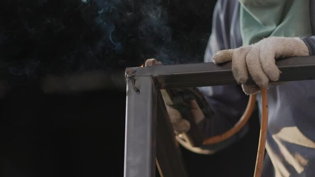 Worker welding steel balcony railing in construction site.