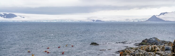 Extremsport - Personen paddeln mit  Kanus durch die Abgeschiedenheit  vorbei an Eisbergen aus...