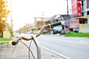 Closeup handlebars of vintage bike which parked on pavement beside the rural road in the city, soft and selective focus.
