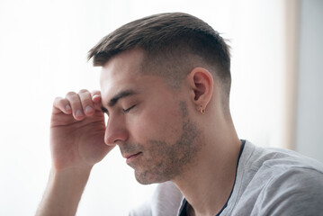 Fototapeta premium Tired man holds his head with his hand close up.