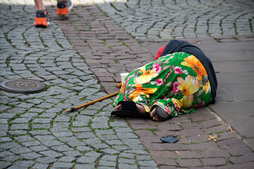 Portrait on back view of homeless romanian woman lying in the street - obrazy, fototapety, plakaty