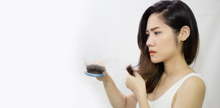 Asian woman are looking a her hair loss and holding a blue comb and hair with worry
