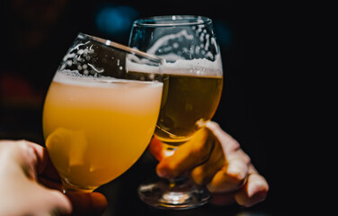 two glass of beer in man hand. Beer glasses clinking in bar or pub