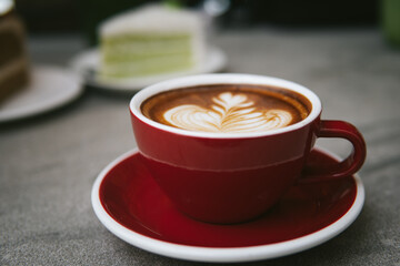 Red cups of hot coffee on vintage wooden table in cafe