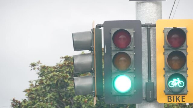 Yellow traffic light or stoplight signal for bicyclists on crossroad, California USA. Bike lane on streets crossing or intersection. Transport infrastructure for safety biking or cycling in city.
