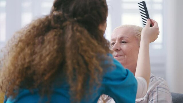 Nurse combing senior woman's hair, living in a nursing home, private care