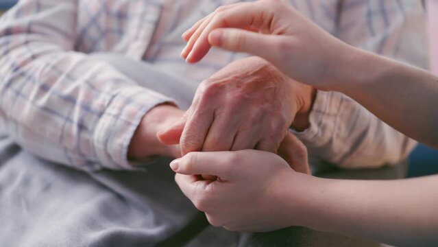 Loving daughter holding wrinkled hands of senior mother, taking care, comforting