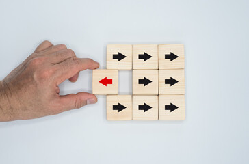 Concept of a wooden block with a red arrow pointing in one way and a black arrow pointing in the...