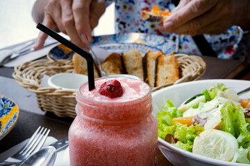 Strawberry shake, vegetable salad and bread on the table