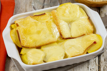 potato with raclette cheese on wooden table