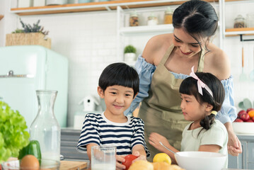 Asian young single mother with son and daughter in kitchen. Enjoy family activity together.