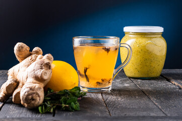 Tea in a glass cup. Tea with honey and mint. Bright yellow tea on a blue background. Tea composition.