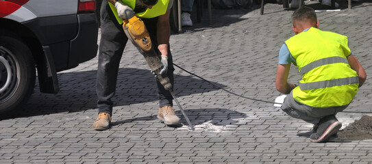 Duas pessoas do sexo masculino a trabalhar no exterior, martelo pneumático, fazer um furo no chão de uma via publica em ambiente citadino