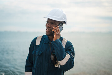 Black maritime worker speaking on mobile phone