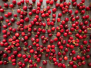 Cherry fruits, flat lay. Heap of cherries on dark wooden table, full frame, top view. Summer fruit.