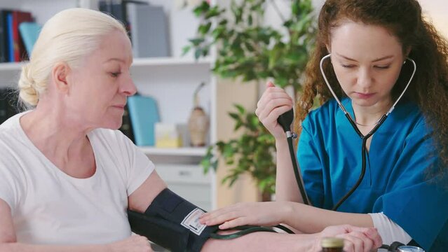 Woman general practitioner measuring senior woman's blood pressure, good results
