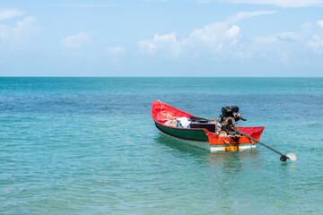 A fishing boat with a motor in the middle of the blue sea. Red boat on blue water