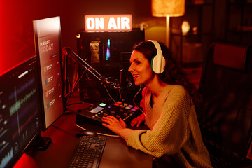 Joyful young adult Caucasian woman with long curly hair wearing casual outfit and headphones...