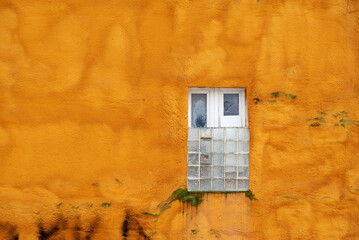 Vieux mur peint en orange avec une fenêtre