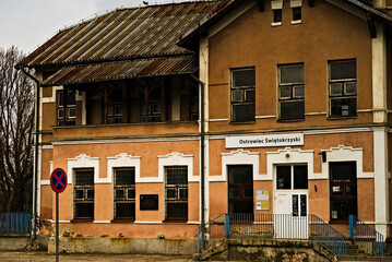 Stary , zabytkowy budynek dworca kolejowego w Ostrowcu Świętokrzyskim . Stacja kolejowa z dachem krytym blachą falistą , pamiątkową tablicą i szyldem z nazwą miasta . Znak zakazu postoju .