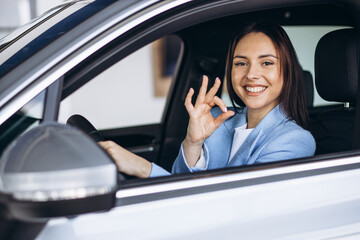 Woman sitting in a car and showing okay sign