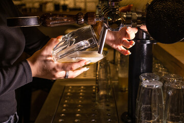 bartender pours beer into a glass