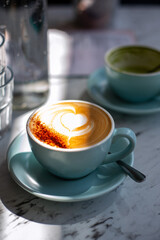 Latte or Cappuccino Coffee with foam latte art heart shape on top in cafe with strong shadows