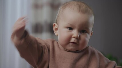 Cute baby boy child waving his hand with a bye bye gesture and laughing